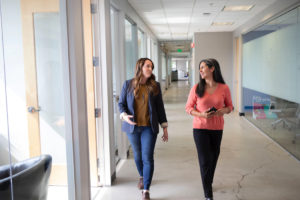 Two business women walk through the hallway of the office space