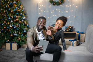 Happy african american family talking on digital tablet in living room interior with tree